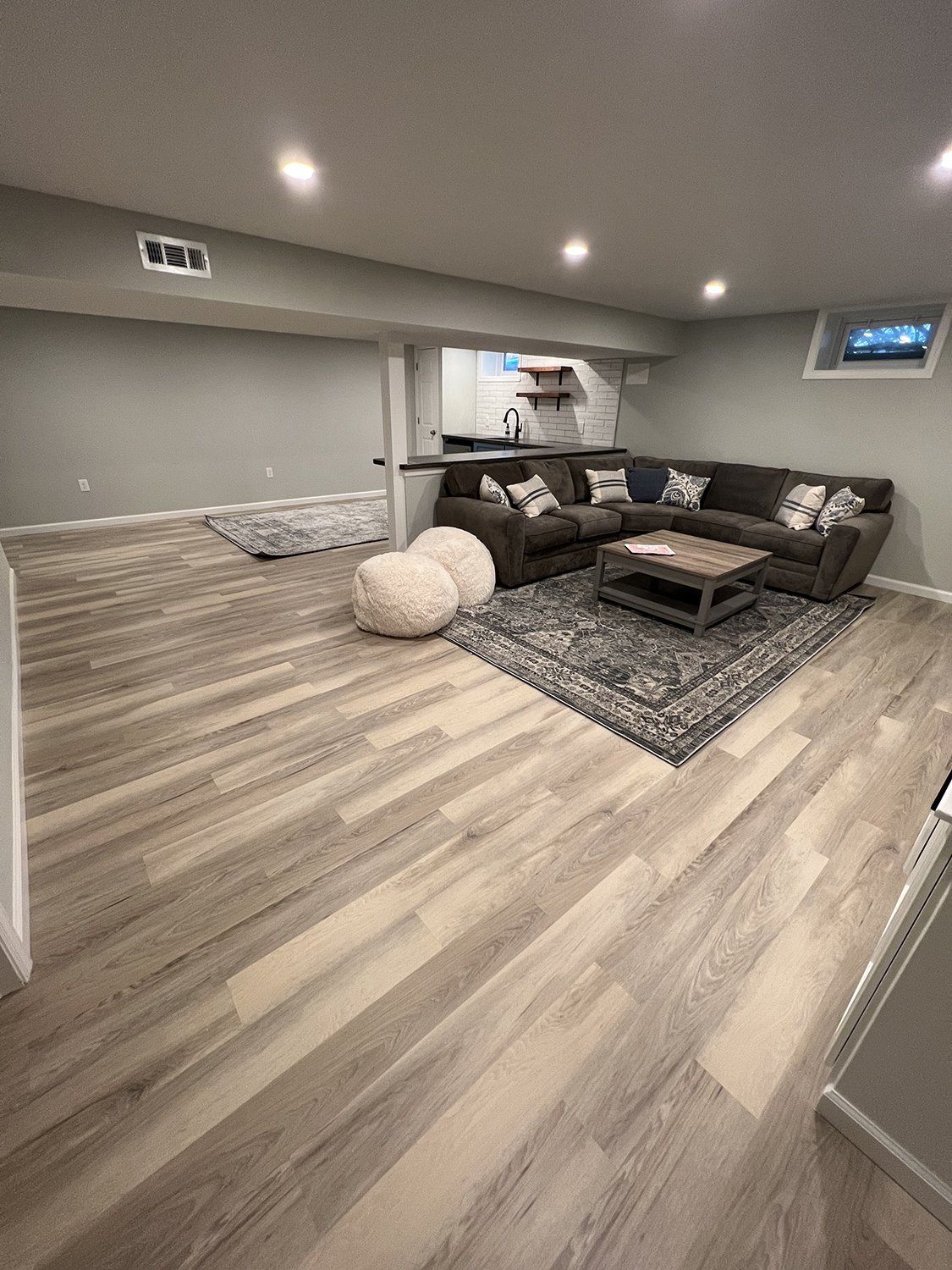 Modern basement living area with gray sofa and built-in storage
